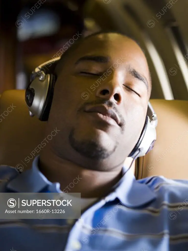 Close-up of a man listening to music on headphones in an airplane