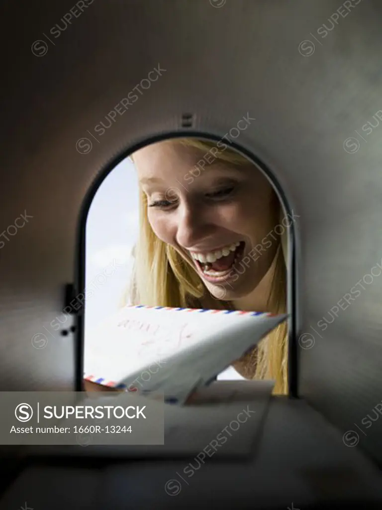Close-up of a young woman looking at mail in a mailbox