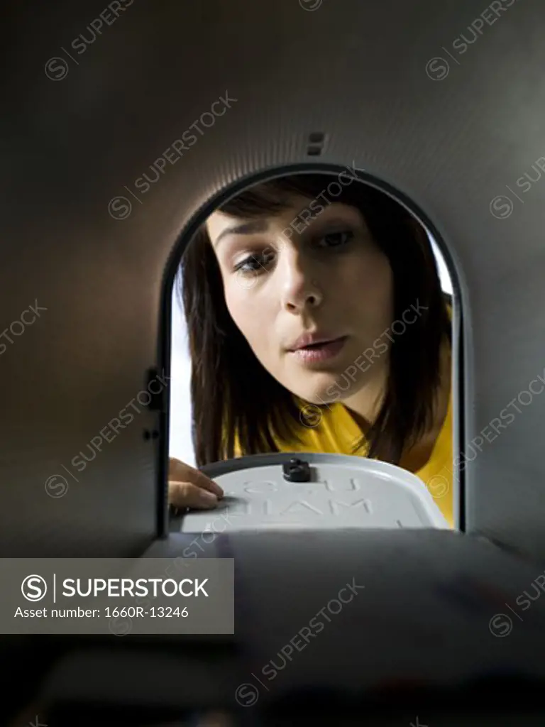 Close-up of a young woman checking a mailbox for mail