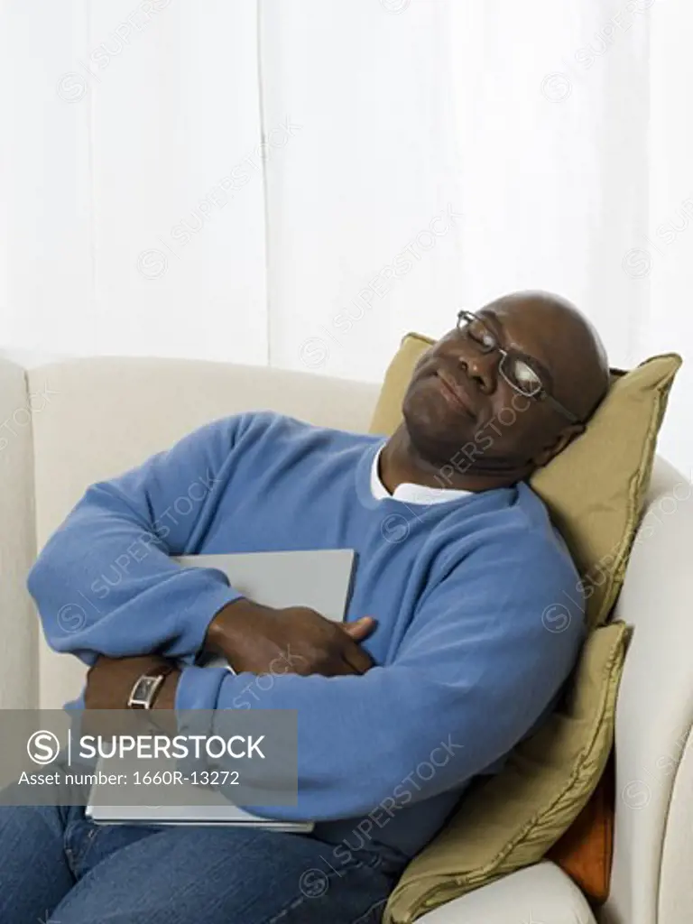 Senior man holding a laptop and relaxing on a couch