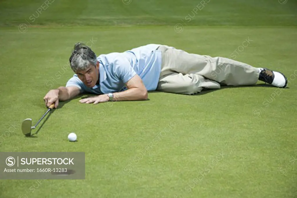 Man lying near a golf hole