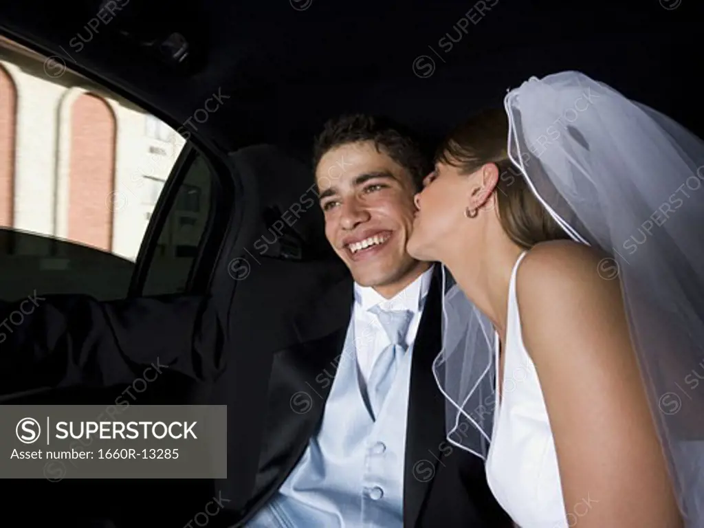 Close-up of a bride kissing her groom in a car