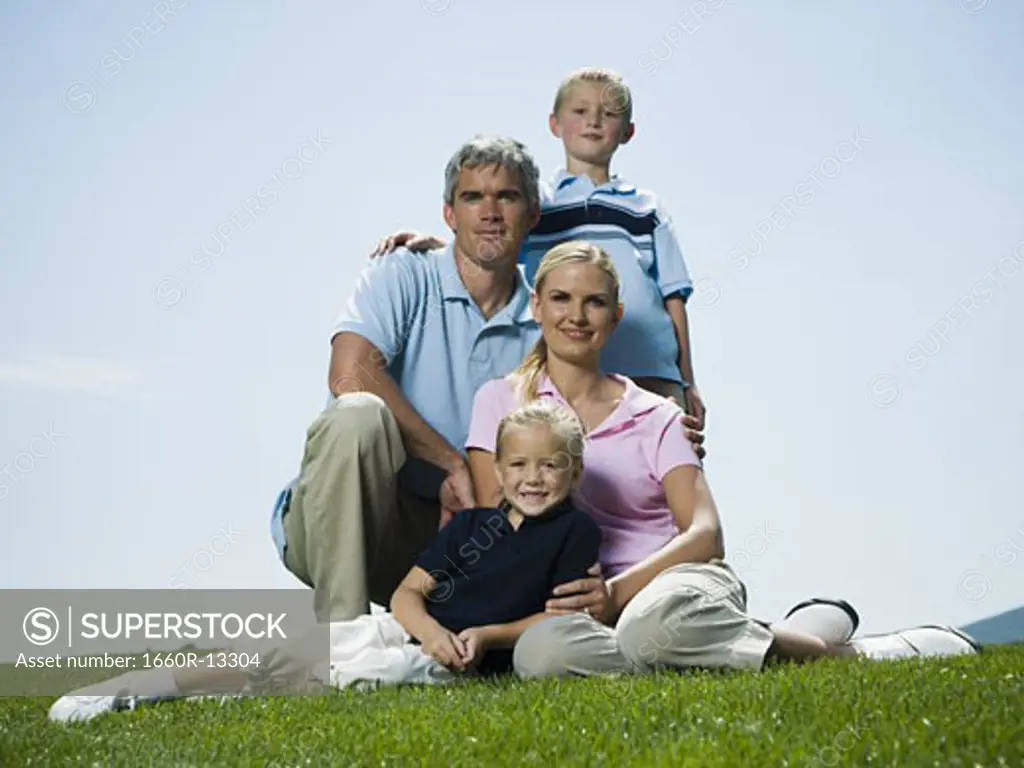 Low angle view of parents and their two children sitting on grass