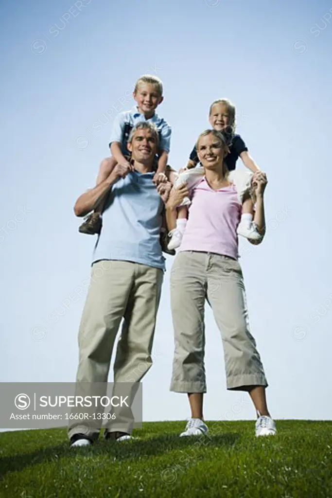 Low angle view of parents carrying their two children on their shoulders