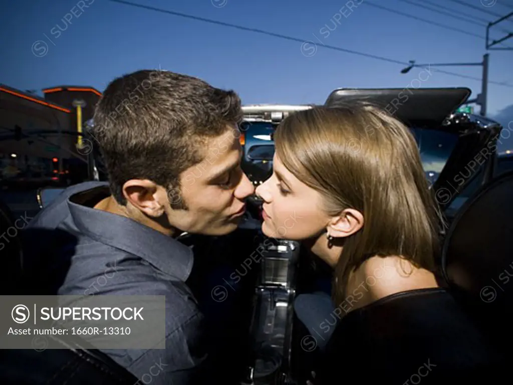 Profile of a young couple sitting in a car and kissing