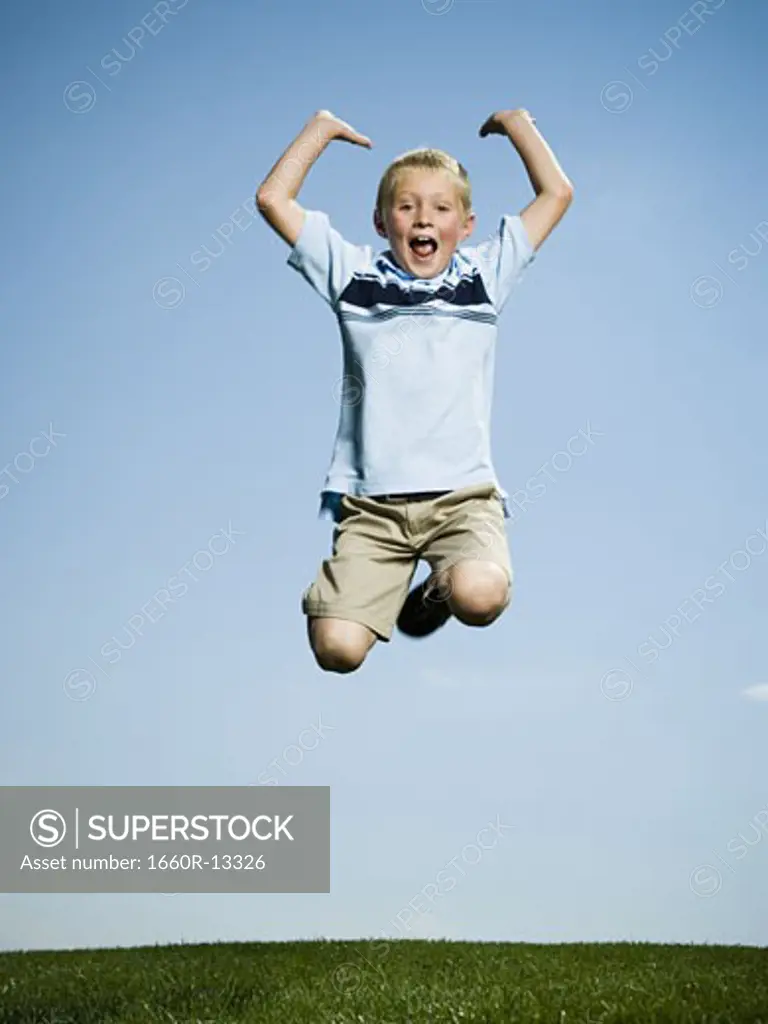 Portrait of a boy jumping with his arms raised