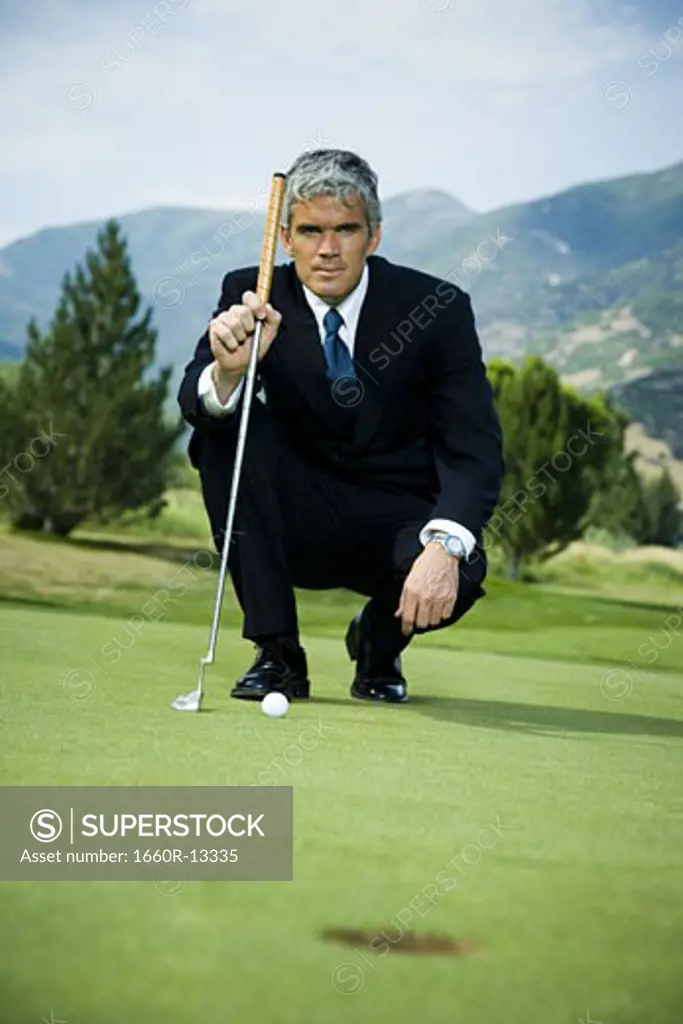Businessman crouching on a golf course