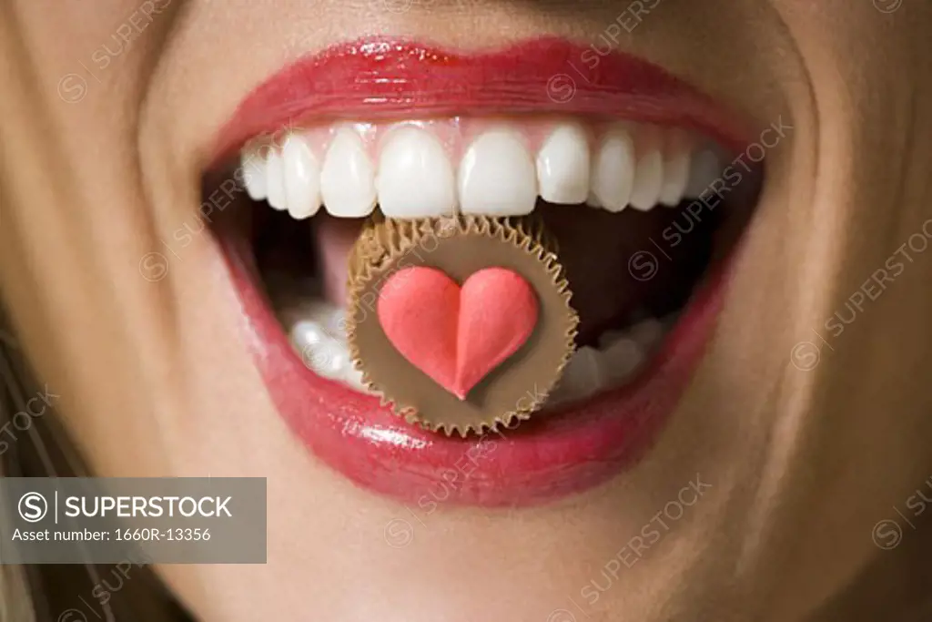 Close-up of a chocolate in a young woman's mouth