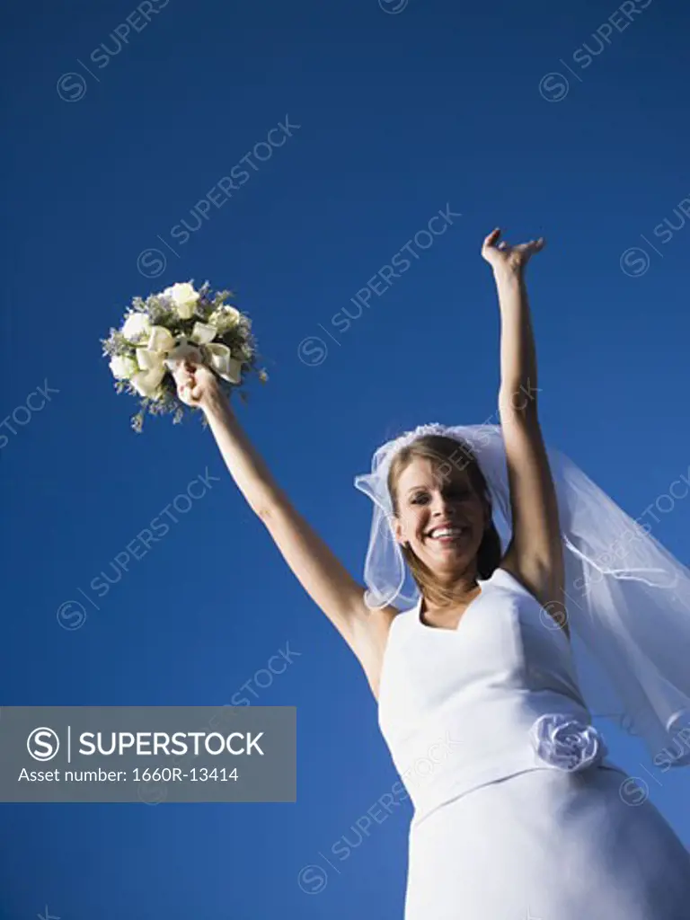 Portrait of a bride holding a bouquet of flowers with her arms raised