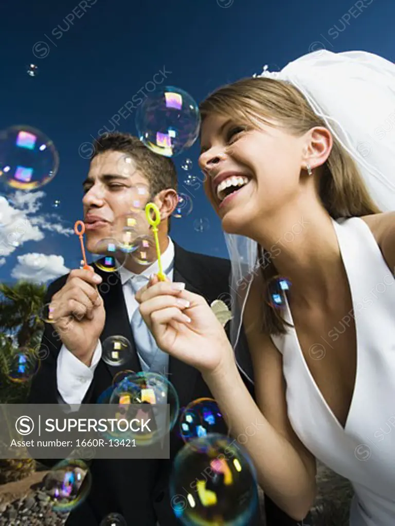 Low angle view of a newlywed couple blowing bubbles with a bubble wand