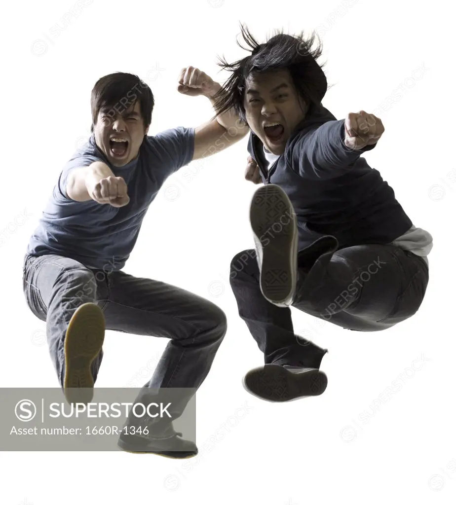 Portrait of two young men jumping and kicking