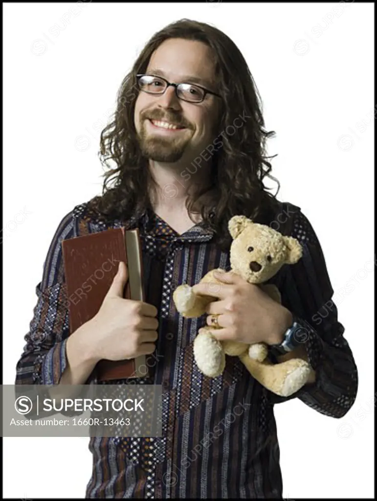 Portrait of a young man holding a book and a teddy bear