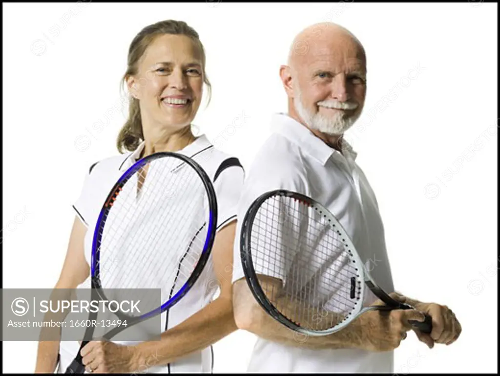 Portrait of a senior couple standing with tennis rackets