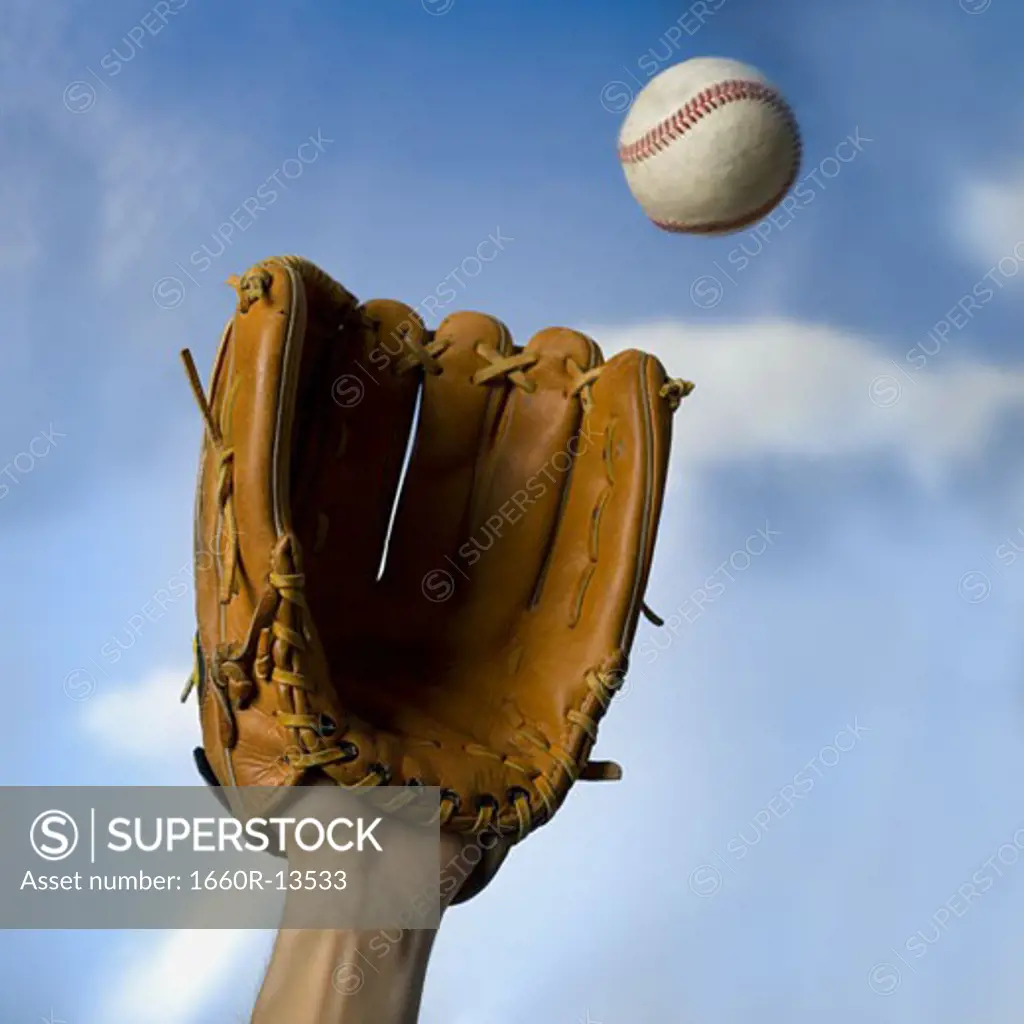 Low angle view of a person's hand catching a baseball with a baseball glove