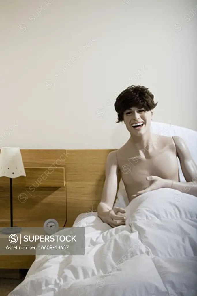 Male mannequin sitting on the bed and laughing