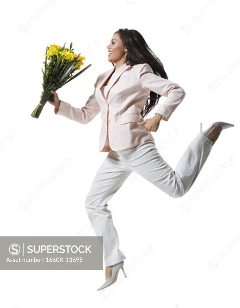 Young woman jumping in mid-air and holding a bouquet of flowers