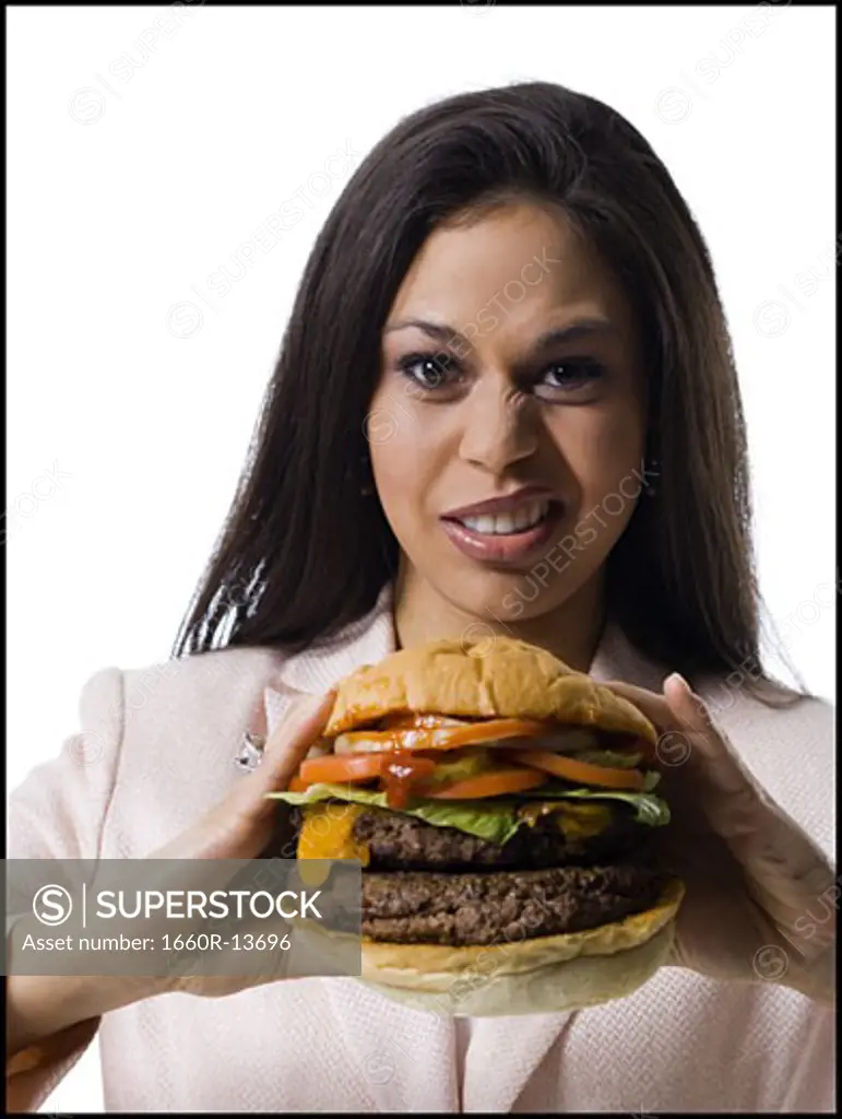 Portrait of a young woman holding a hamburger and making a face