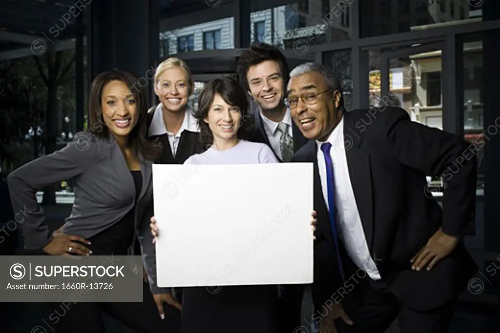 Portrait of five business executives standing with a blank sign