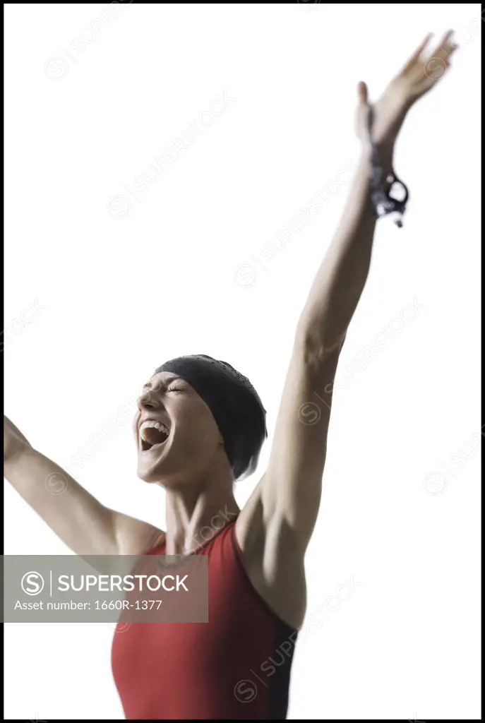 Low angle view of a young woman smiling with her arms raised