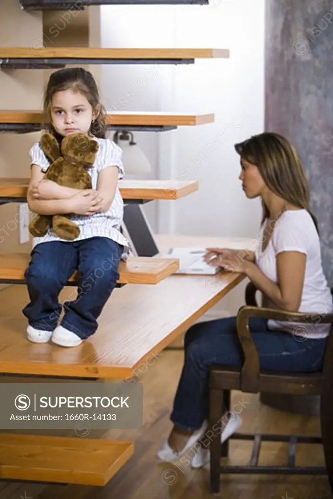 Young girl waiting for mother to finish work on laptop computer