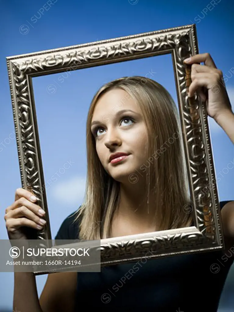 Young woman posing with an empty picture frame