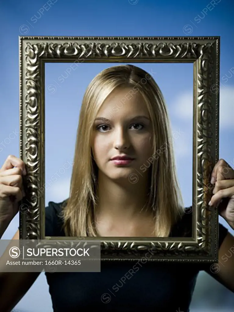 Young woman posing with an empty picture frame
