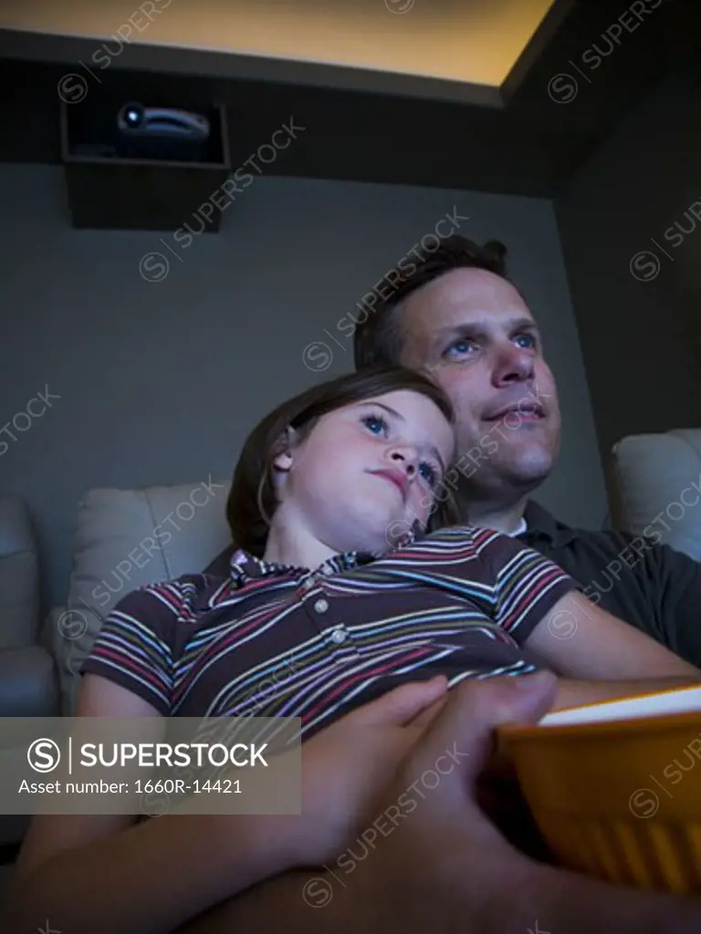 Father and daughters watching movie in home theater