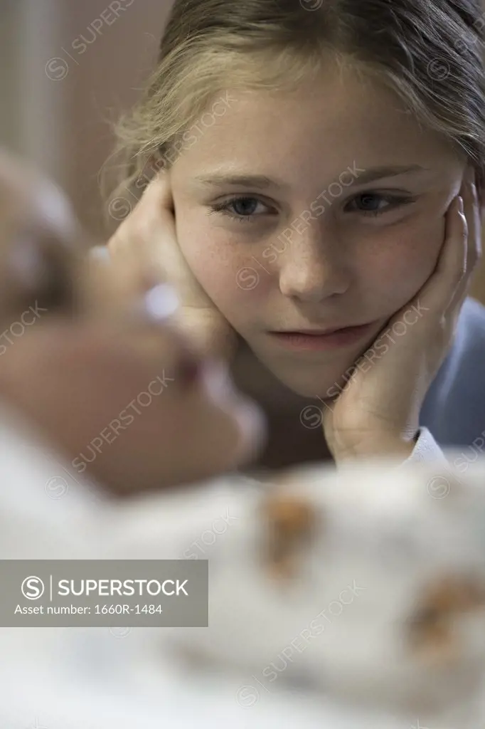 Sister looking at her brother lying in a hospital bed