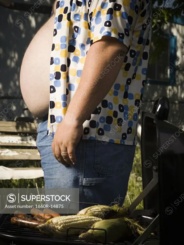 Overweight man by barbecue grill