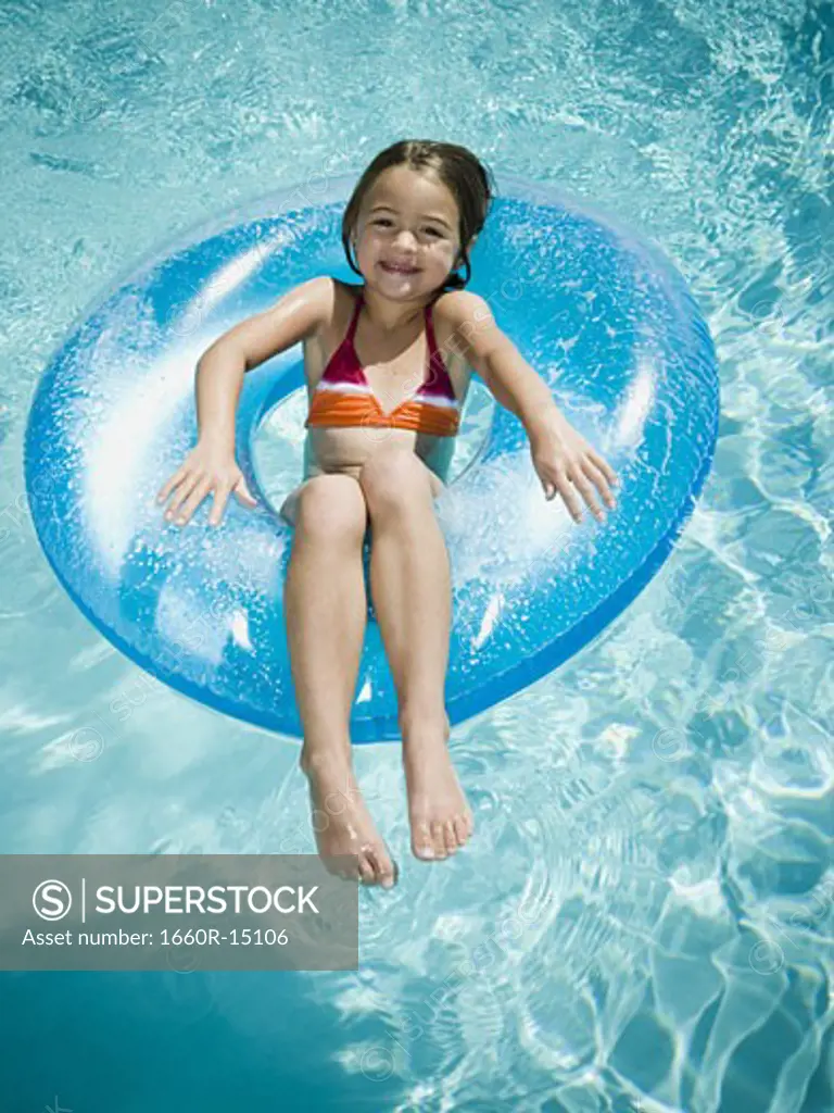 Young girl floating on life ring in swimming pool