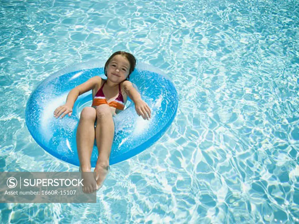 Young girl floating on life ring in swimming pool