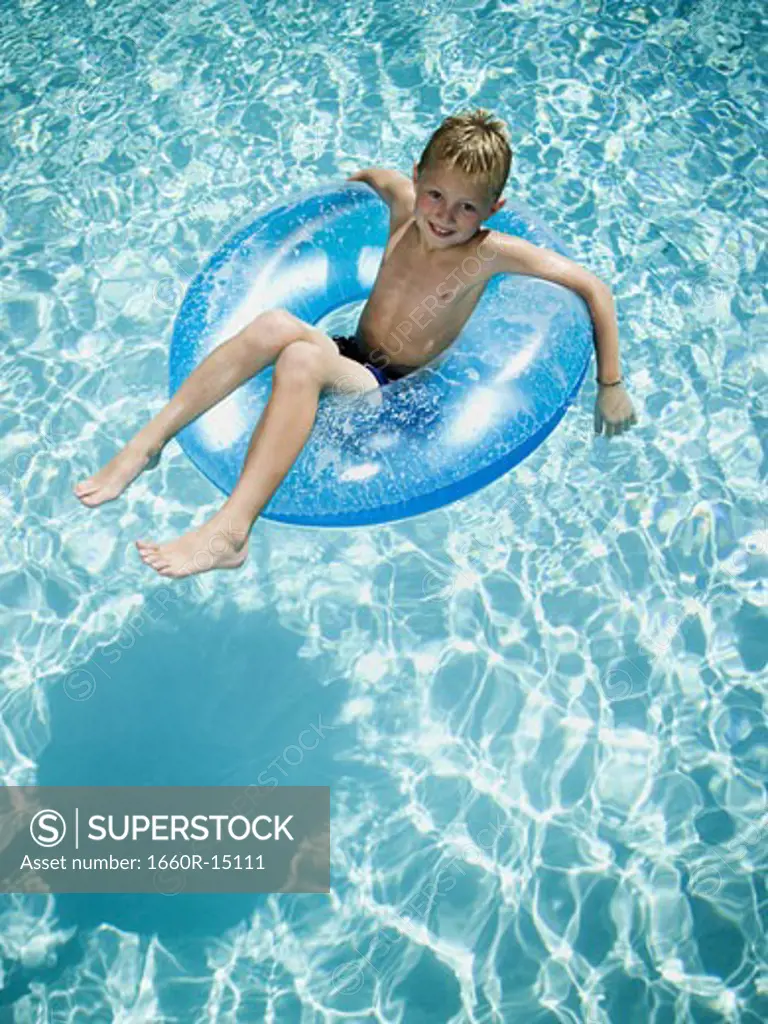 Young boy floating on life ring in swimming pool