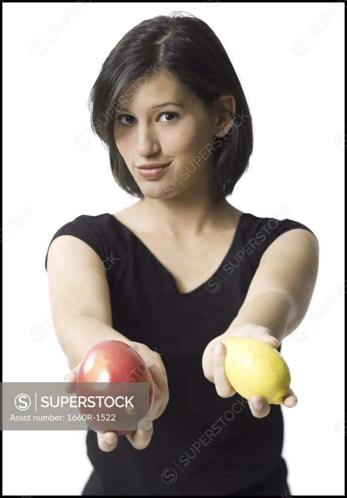 Portrait of a young woman holding a lemon and a mango