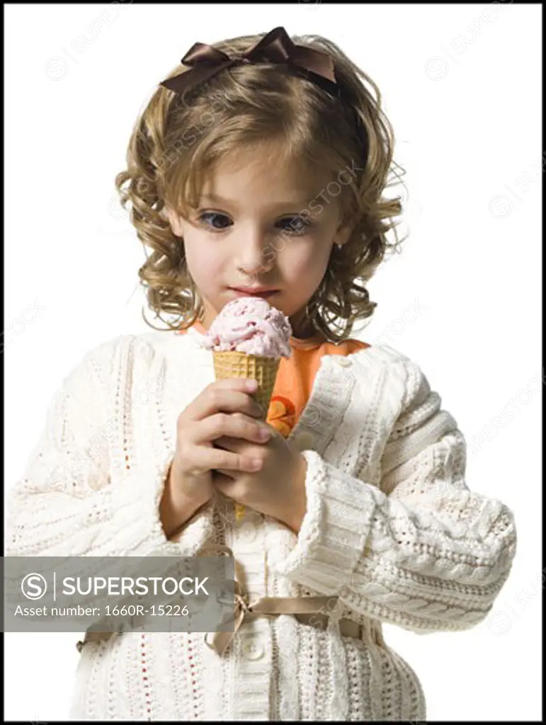 Smiling young girl in white sweater eating ice cream cone