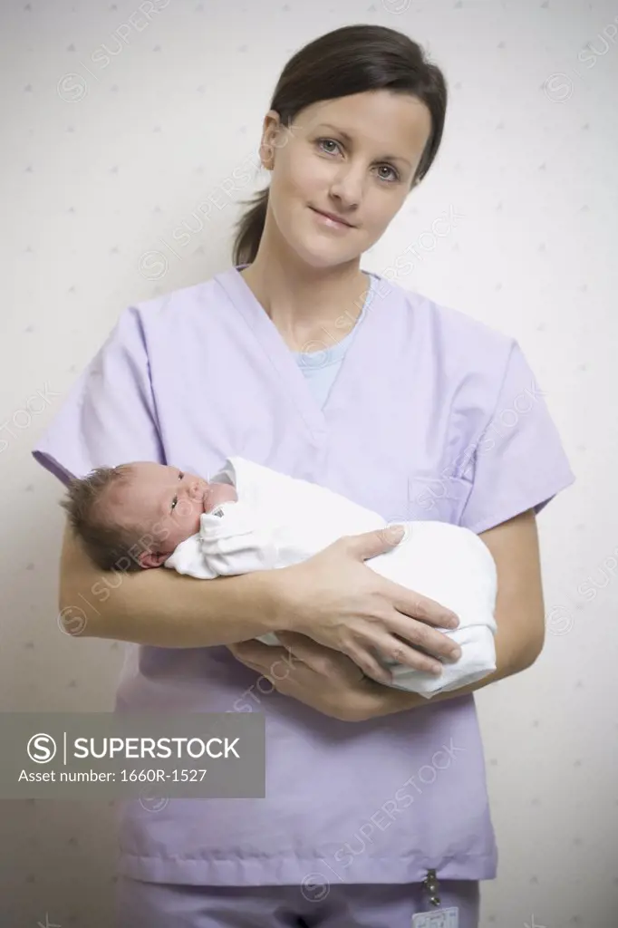 Portrait of a female nurse carrying a newborn baby boy