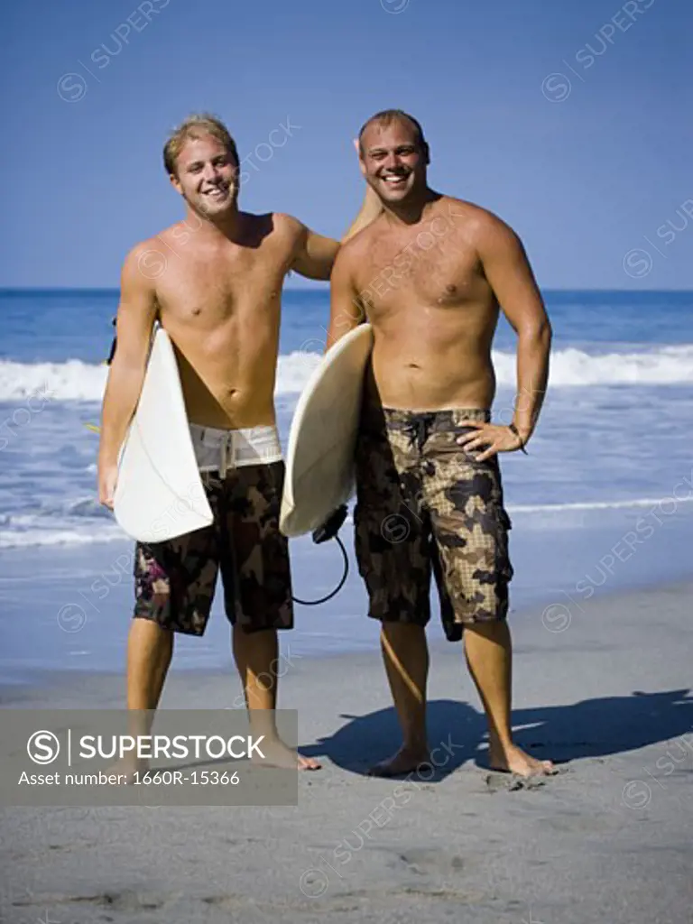 Two males on beach with their surf boards