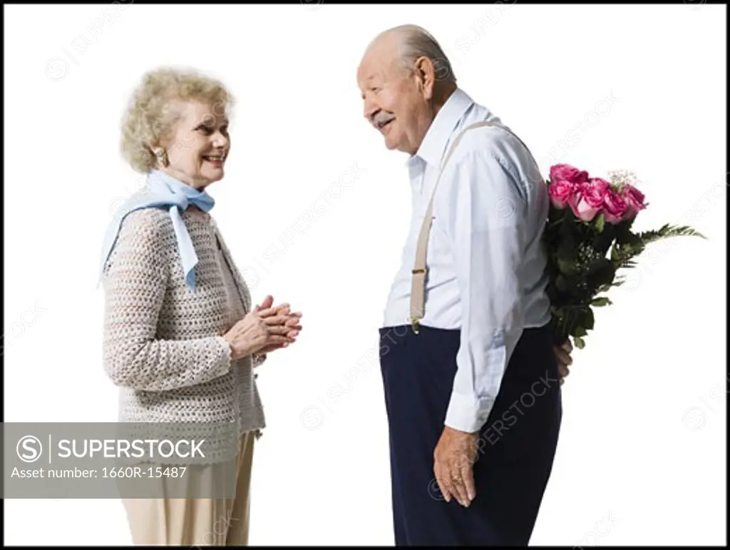 Older man with bouquet of pink roses behind back