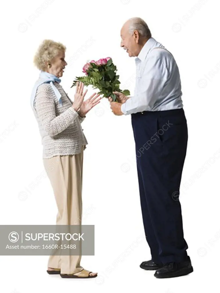 Older man giving wife bouquet of pink roses