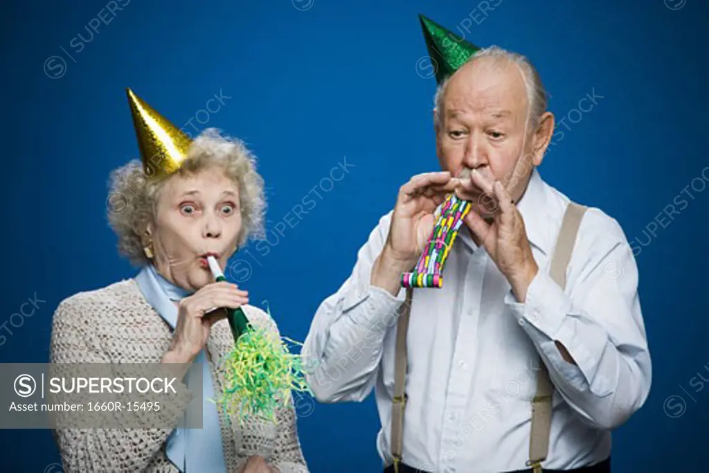Older couple with noisemakers and party hats