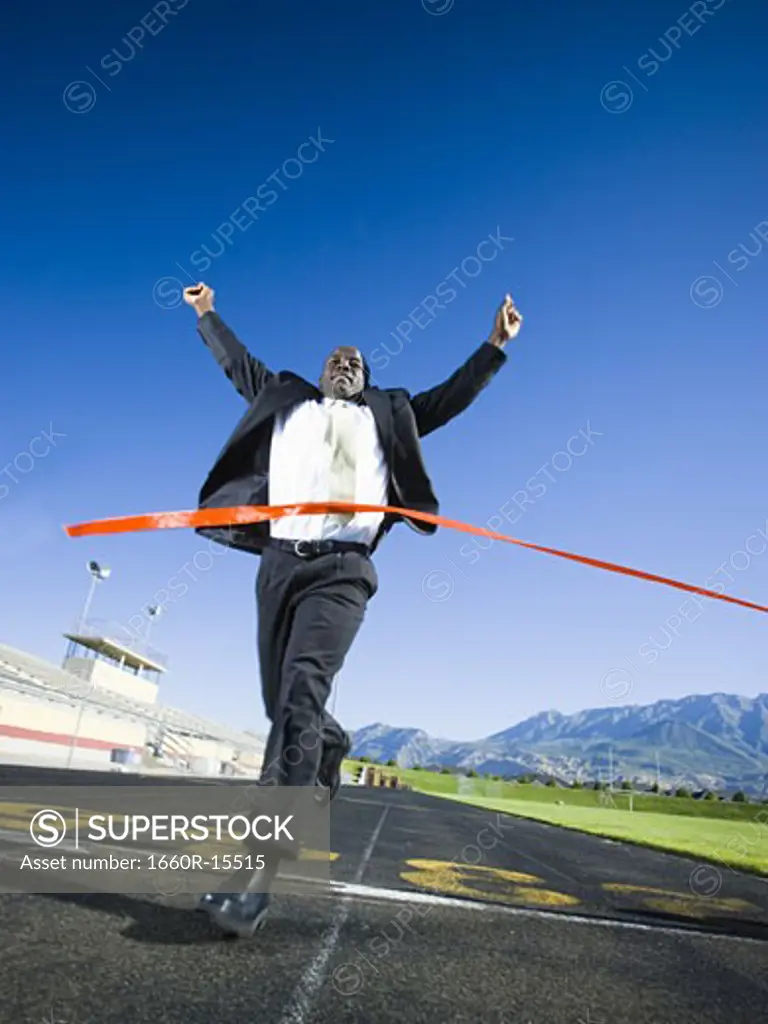 Businessman running and crossing finish line