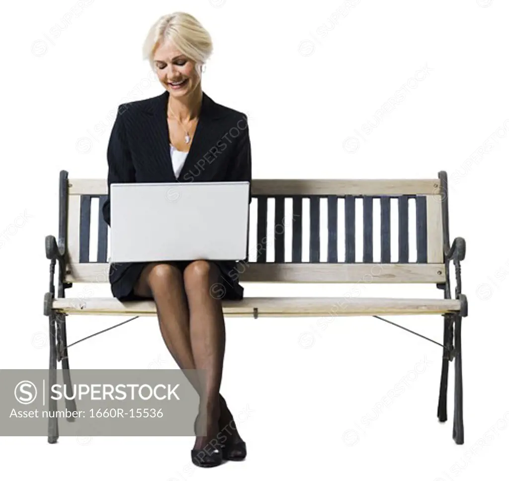 Businesswoman sitting on bench with laptop
