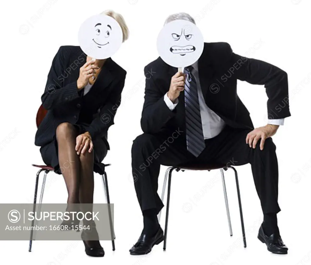 Businessman and businesswoman holding expression masks