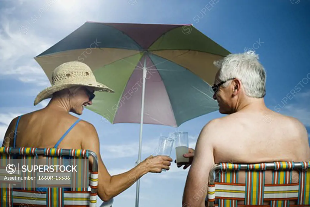 Mature couple at the beach relaxing on deck chairs