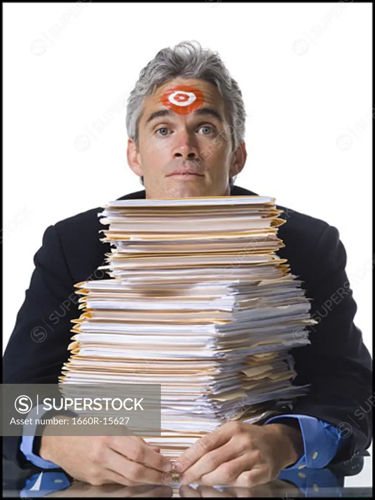 Man with bull's-eye on forehead with stack of papers
