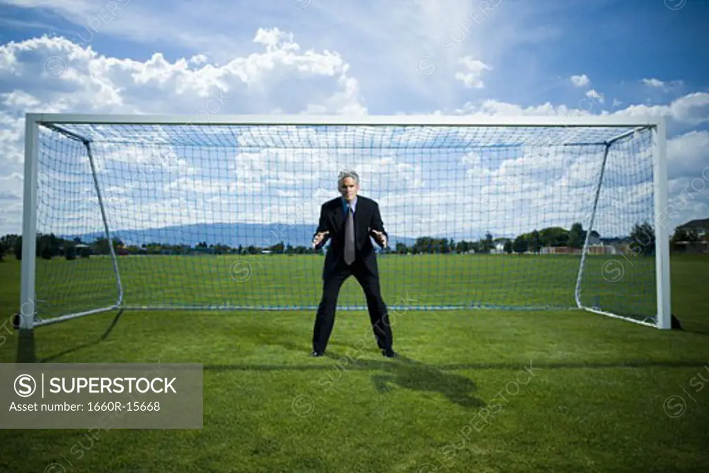 Businessman defending goal on soccer field