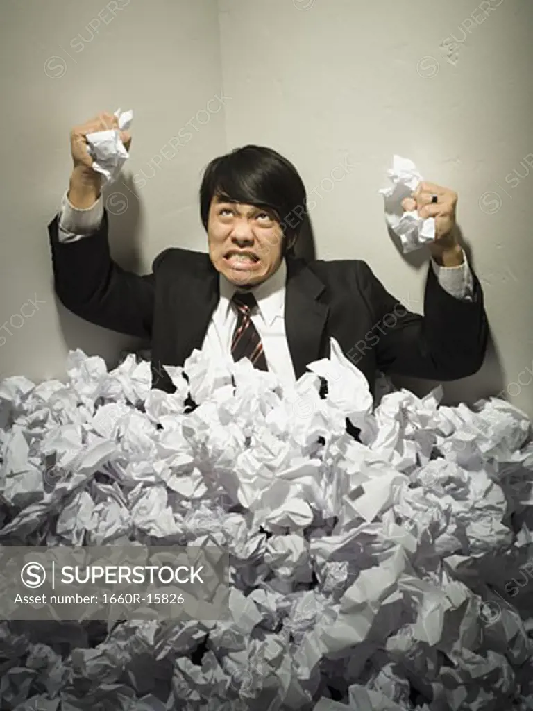 Businessman buried in mountain of crumpled papers