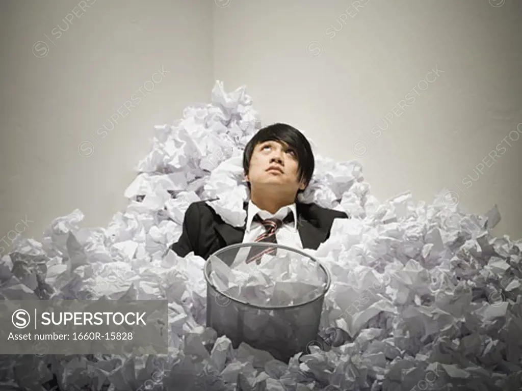 Businessman buried in mountain of crumpled papers
