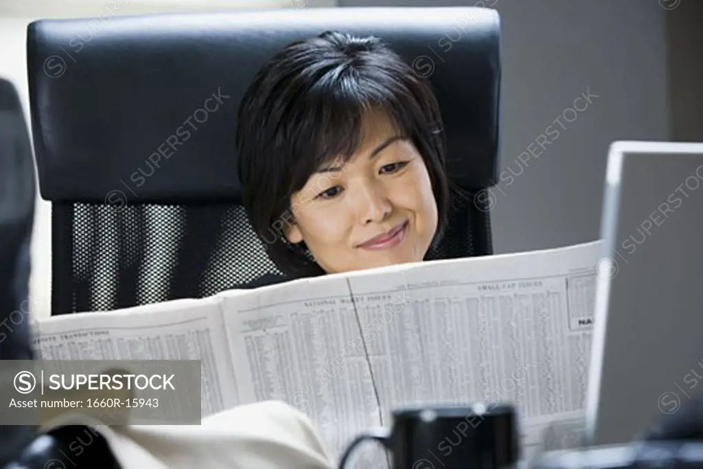 Woman reading financial pages of newspaper
