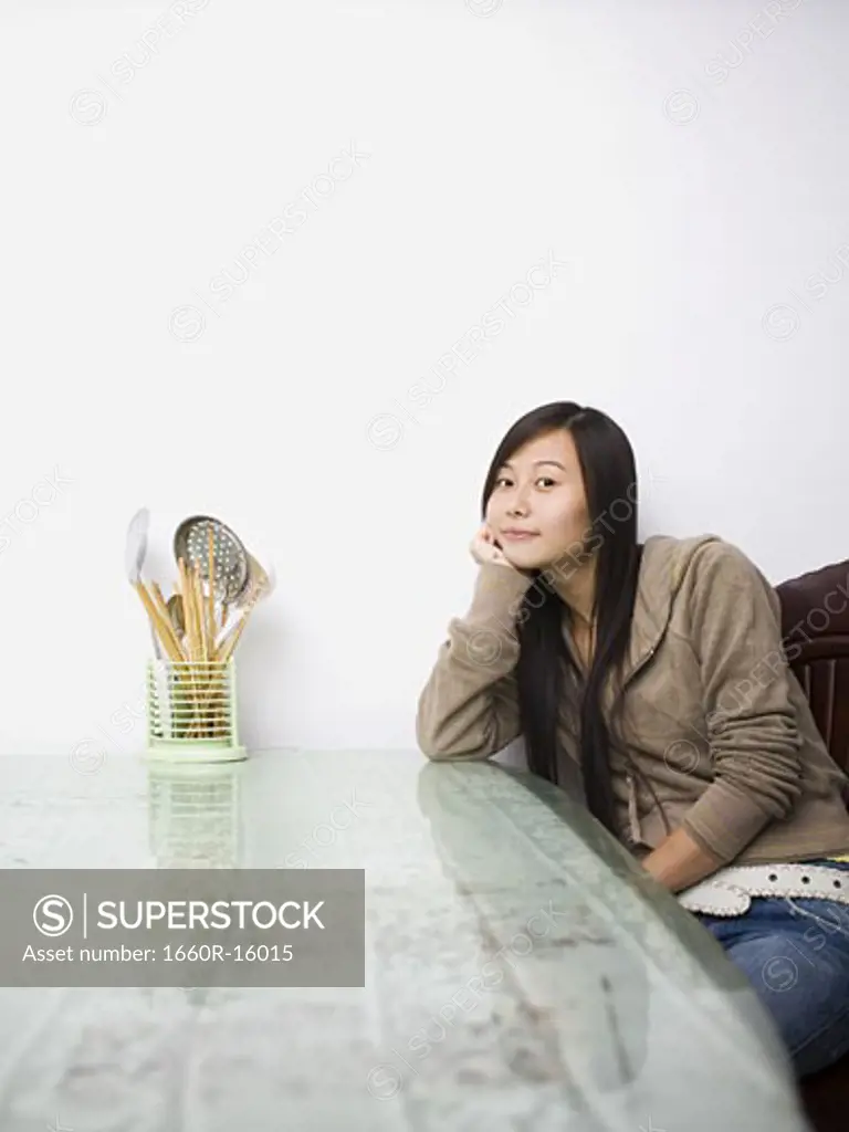 Woman sitting at a table with kitchen utensils
