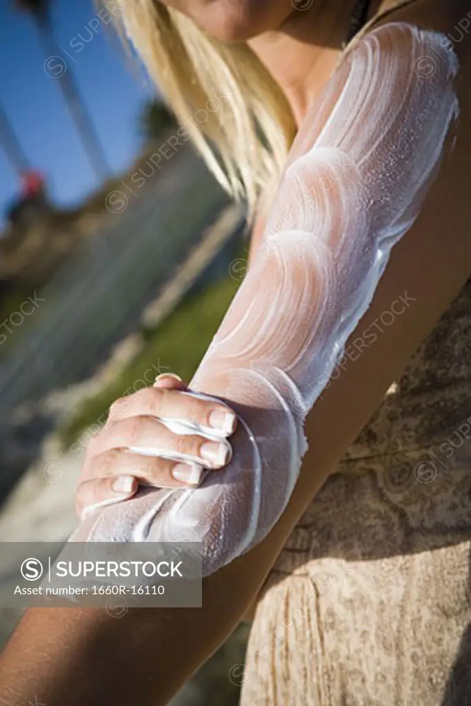Woman sunbathing and applying lotion
